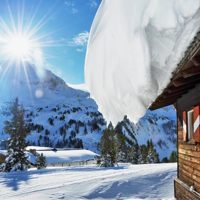 Schneebedeckte Almhütte in sonniger Winterberglandschaft