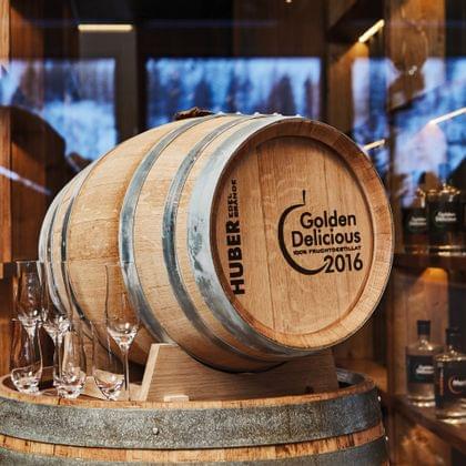 Holzfass Golden Delicious 2016 mit Gläsern vor Regal mit Spirituosenflaschen