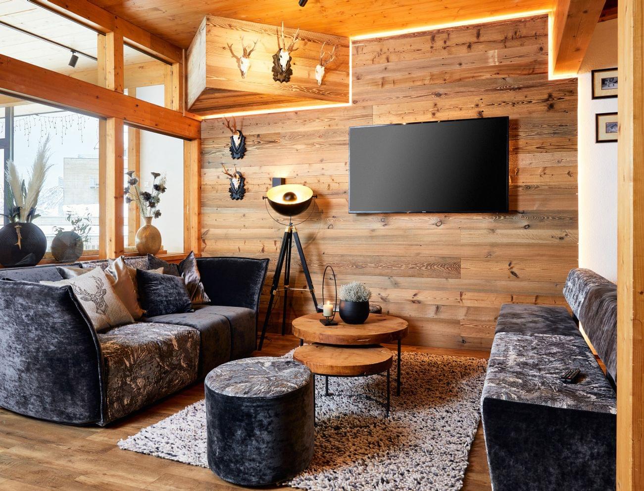 Gemütliches Alpen-Wohnzimmer mit Holzverkleidung, Samtsofas und moderner Dekoration
