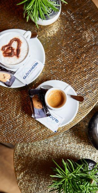 Espresso und Cappuccino mit Keks auf elegantem Tisch mit Pflanze