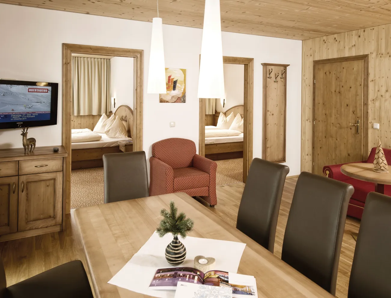 Cozy alpine hotel suite with wooden furniture, dining area, and two double bedrooms