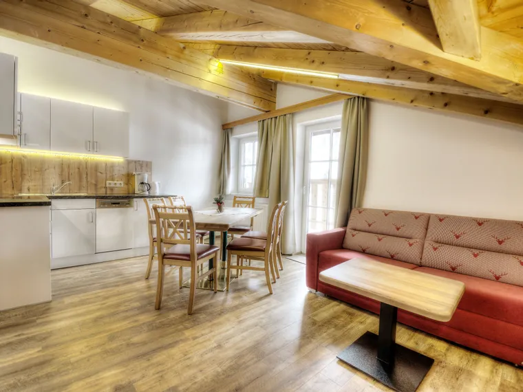 Cozy alpine apartment kitchen and dining area with wooden ceiling and modern furnishings