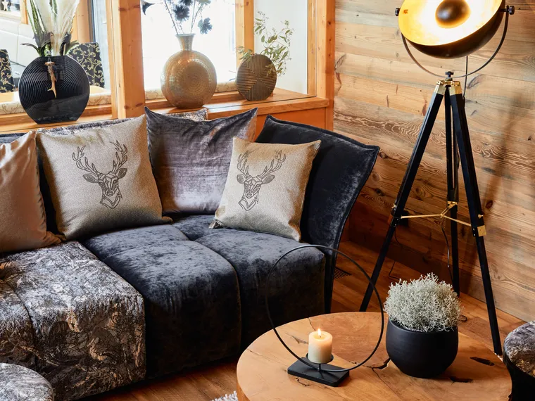 Cozy rustic living room with velvet sofa, deer motif pillows, and tripod floor lamp