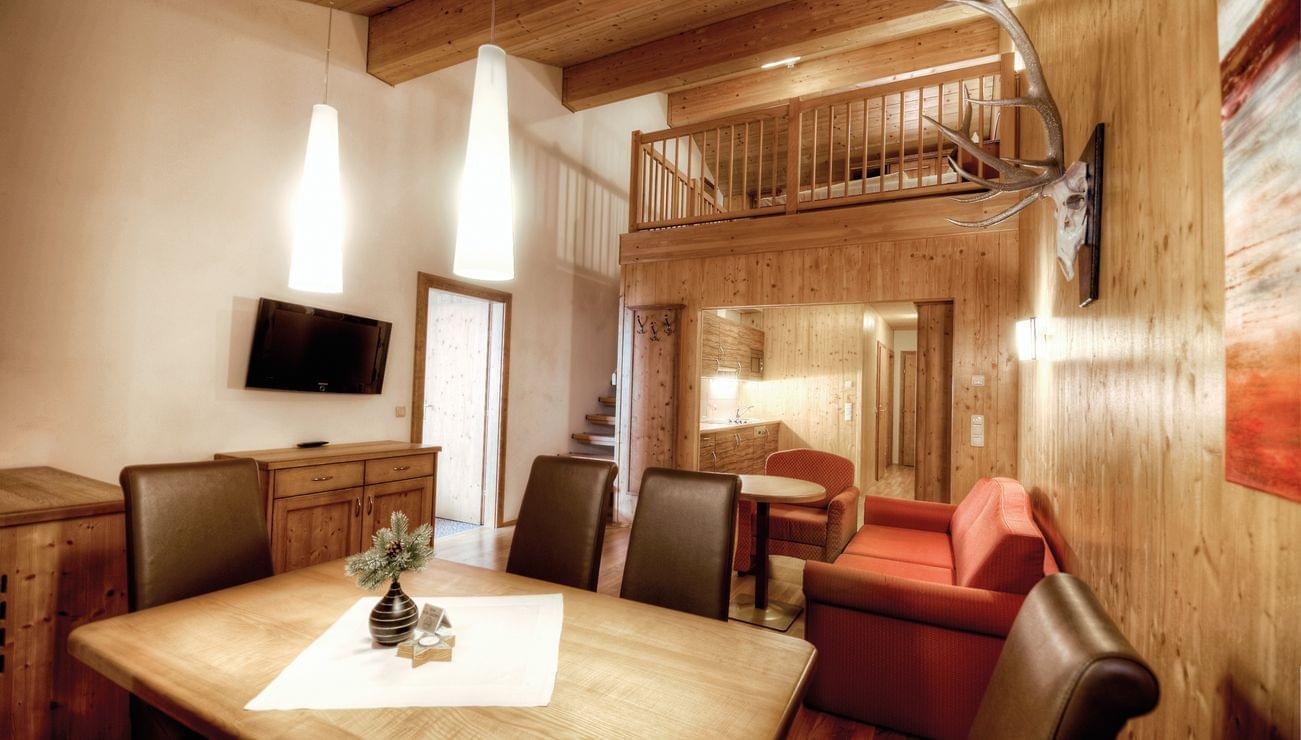 Gemütliches Chalet-Wohnzimmer mit Holzwänden, Essbereich und offener Galerie