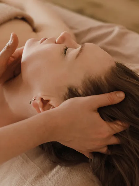 Woman receiving relaxing head massage in spa on massage table