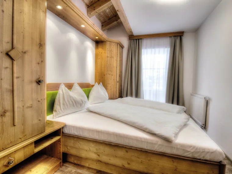 Gemütliches Schlafzimmer mit Doppelbett, Holzverkleidung und Tageslicht