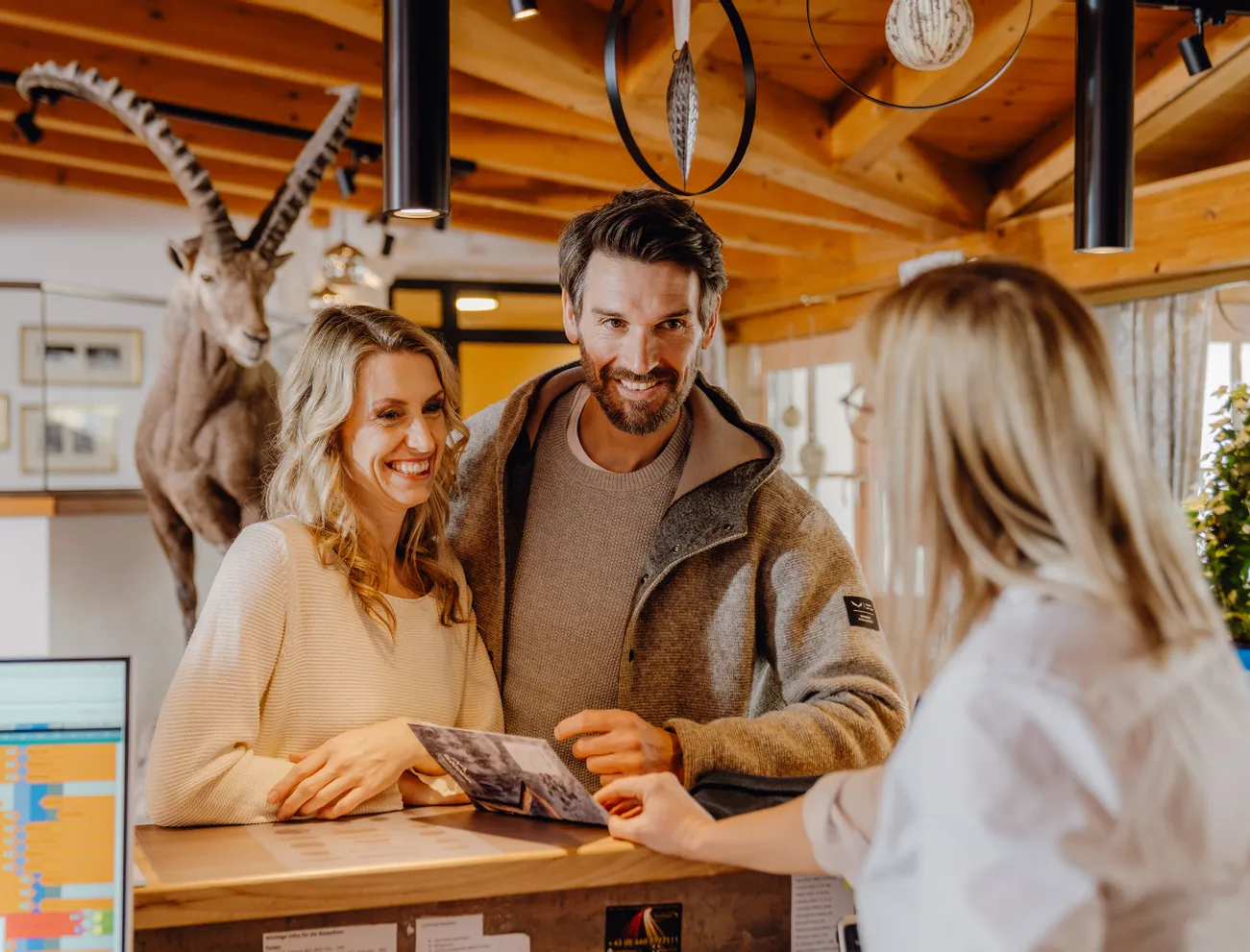 Smiling couple at hotel reception desk talking with receptionist