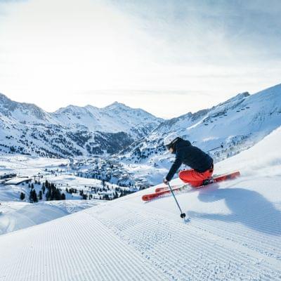 Skier carving down a freshly groomed slope in the snowy Alpine mountains