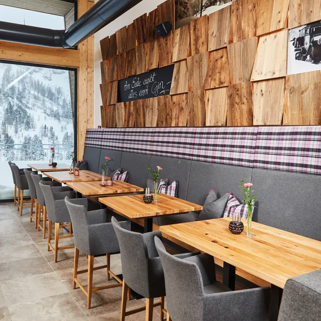 Cozy alpine restaurant interior with wooden tables, grey chairs, and mountain view