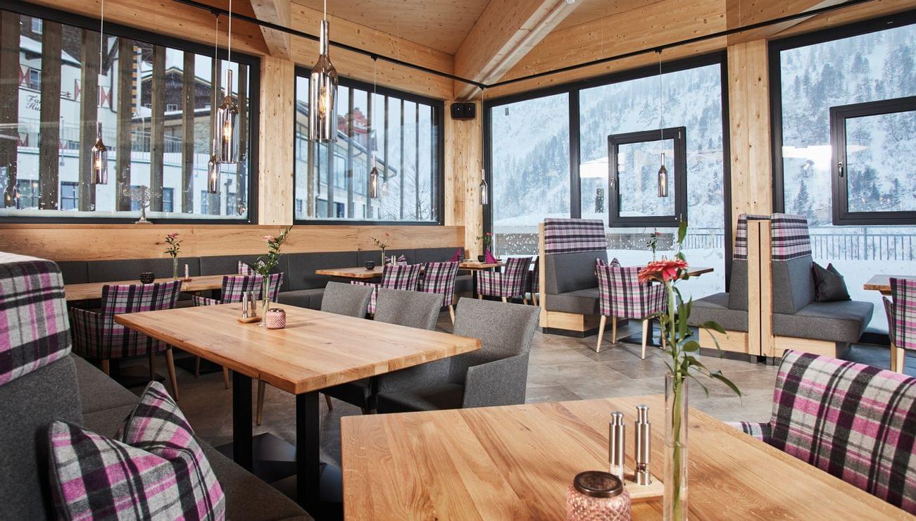 Gemütliches Restaurant mit Holzmöbeln und Blick auf schneebedeckte Berge