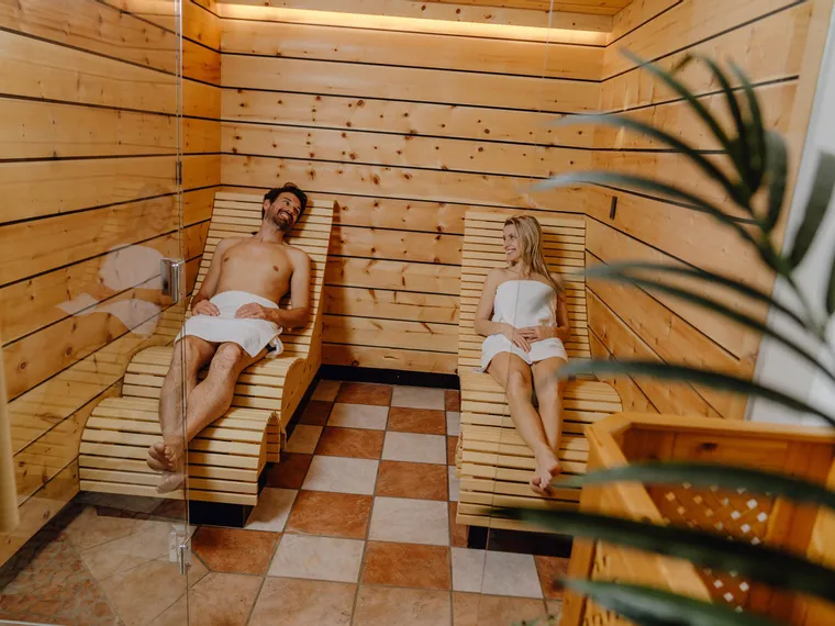 Paar entspannt auf Holzliegen im Wellnessbereich einer Sauna