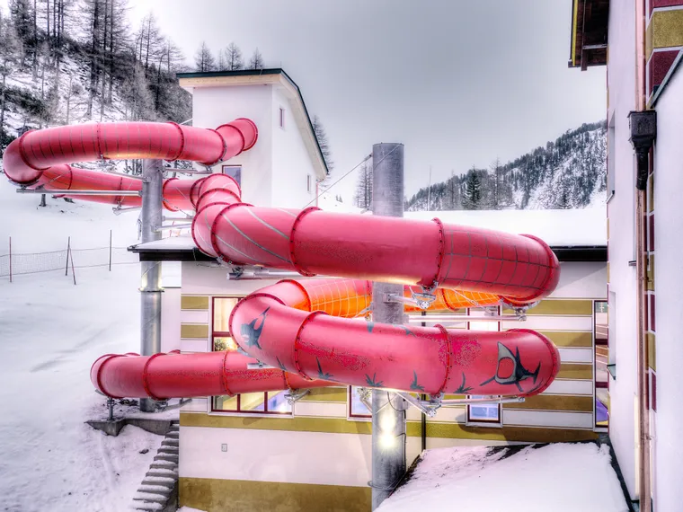Red waterslide outdoors at a snowy alpine resort building