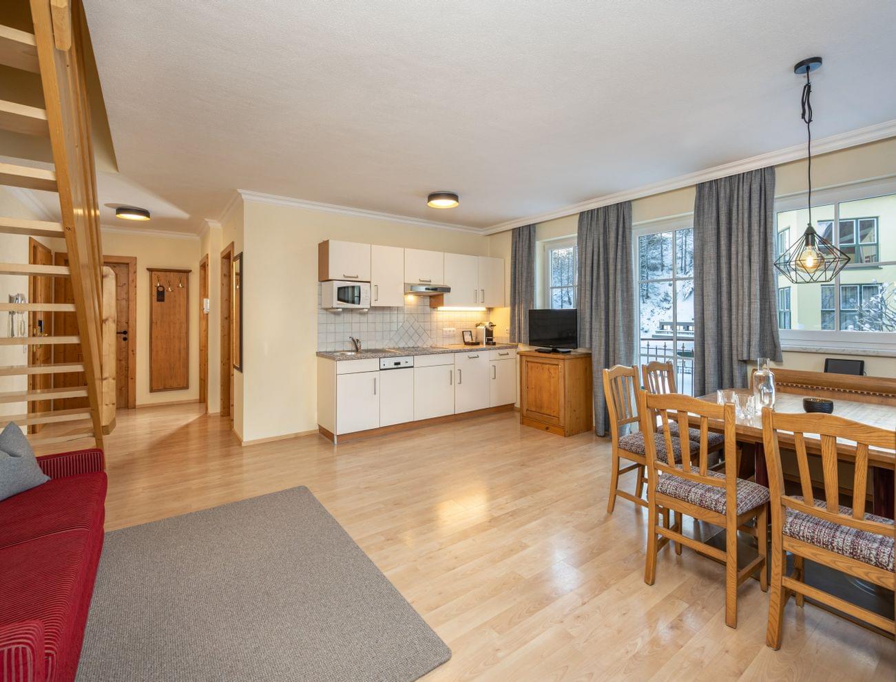Cozy holiday apartment with open kitchen, wooden dining area, sofa, and stairs to upper level