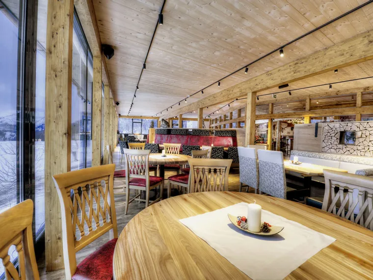 Cozy alpine restaurant interior with wooden decor and panoramic snowy mountain view