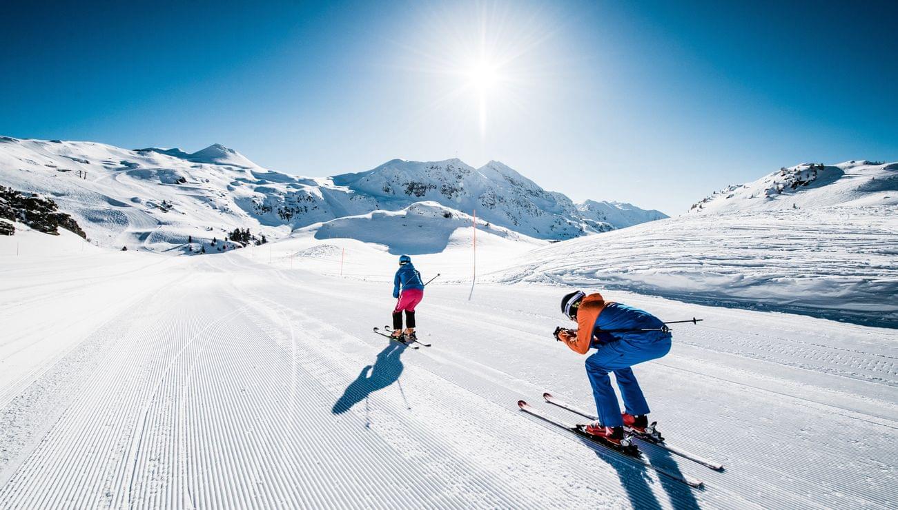 Two skiers on a sunny slope in the snowy Alps
