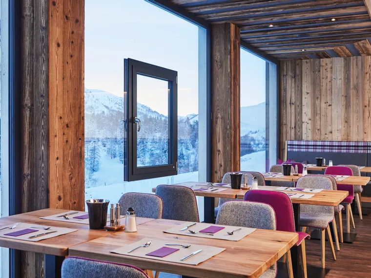 Modernes Restaurant mit Holzdecken und Panoramablick auf verschneite Berge