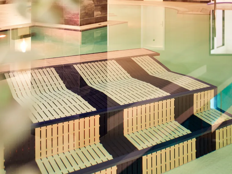 Unterwasser-Liegen aus Holz in einem Spa-Innenpool mit ruhigem Wasser