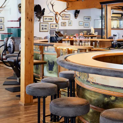 Rustic bar interior with wooden decor, deer motifs, and upholstered stools