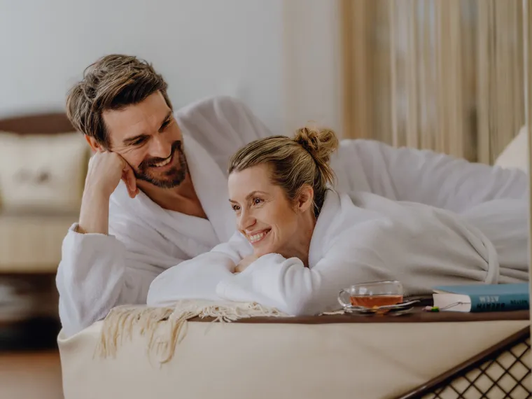 Couple in white bathrobes relaxing together in a spa lounge