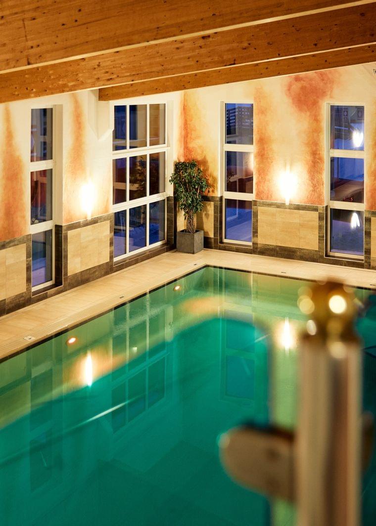 Beleuchteter Innenpool mit Holzdecke und Wandmalerei in warmen Farben