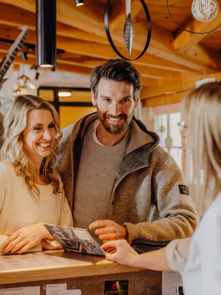 Smiling couple at hotel reception desk talking with receptionist
