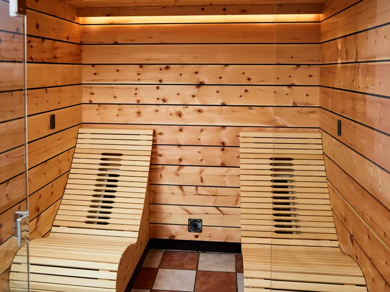 Moderne Holzsauna mit zwei ergonomischen Liegen und warmer Ambientebeleuchtung