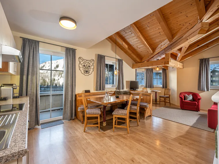 Cozy alpine apartment with wooden ceiling, dining area, and mountain view