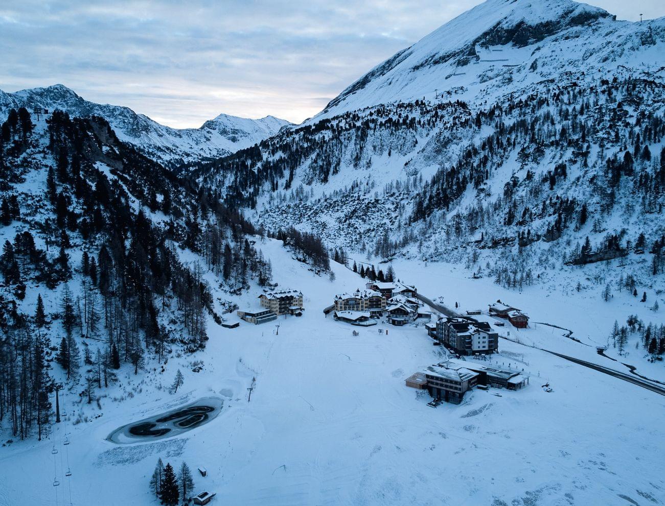 Verschneites Alpendorf in einem von Bergen umgebenen Tal im Winter