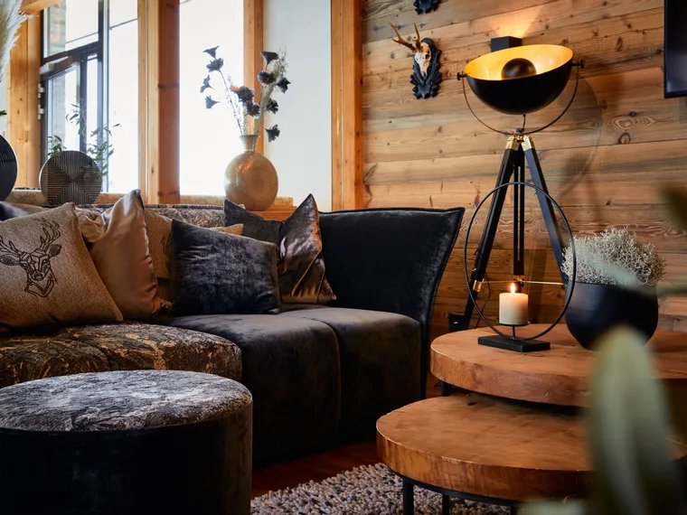 Cozy rustic living room with velvet sofa, decorative pillows, wood accents and soft lighting