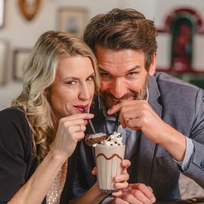 Paar teilt einen Schokoladen-Milchshake mit Strohhalmen in gemütlichem Café