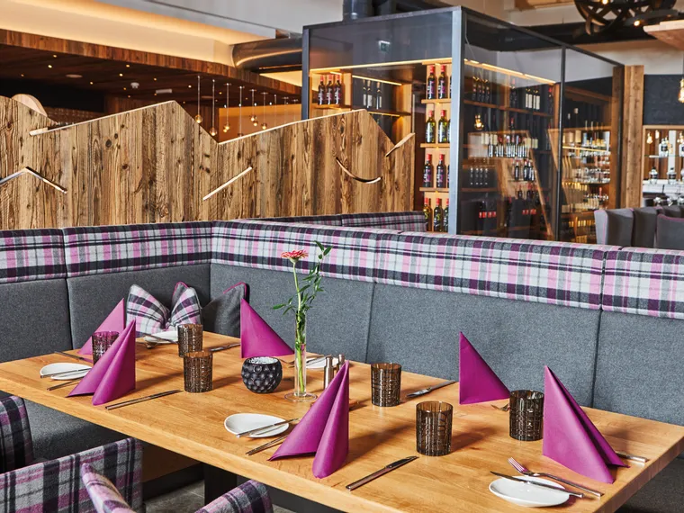 Modern eingerichtetes Restaurant mit gedecktem Holztisch und lila Servietten