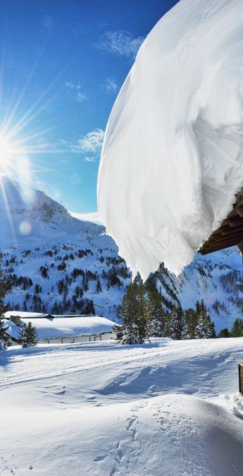 Schneebedeckte Almhütte in sonniger Winterberglandschaft