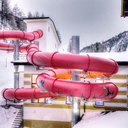 Red waterslide outdoors at a snowy alpine resort building