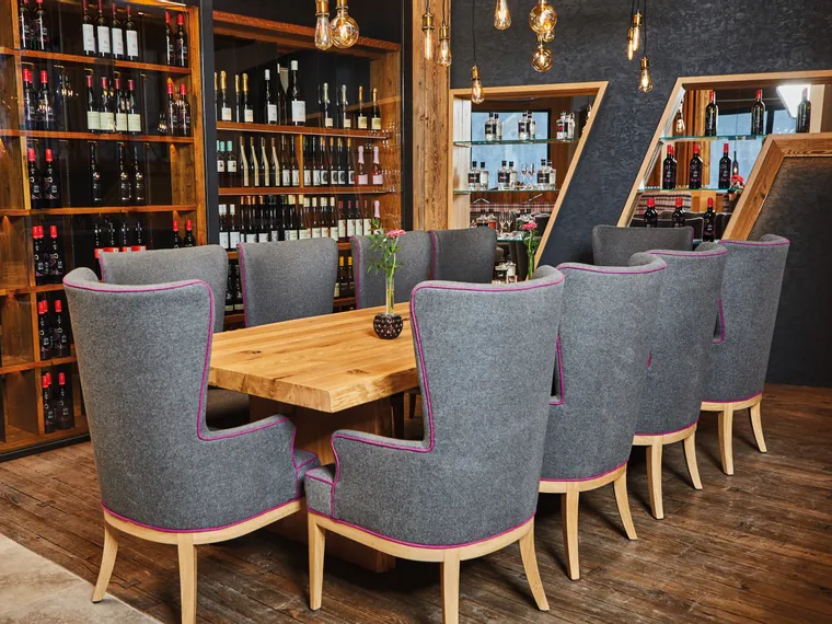 Elegant wine cellar dining area with gray upholstered chairs and wooden table