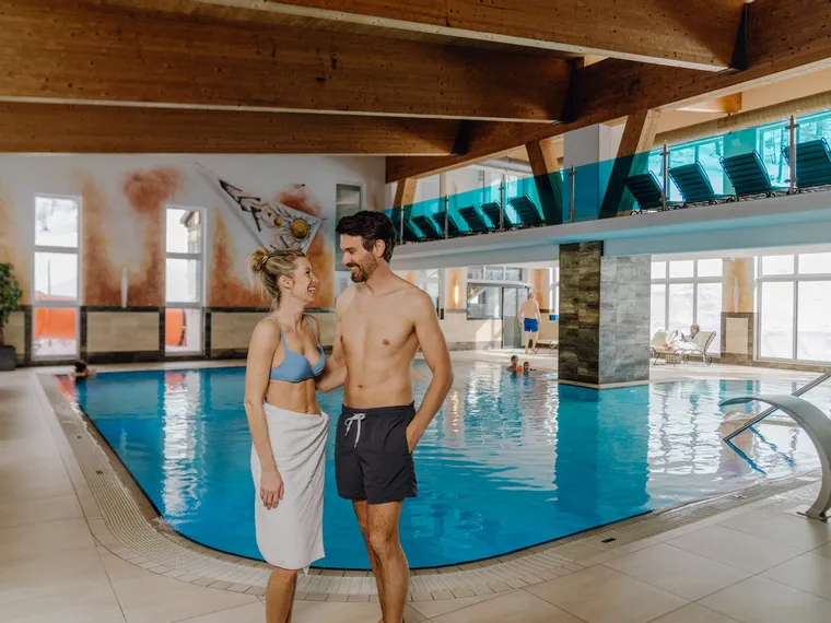 Paar lächelt am Innenpool im Wellnesshotel