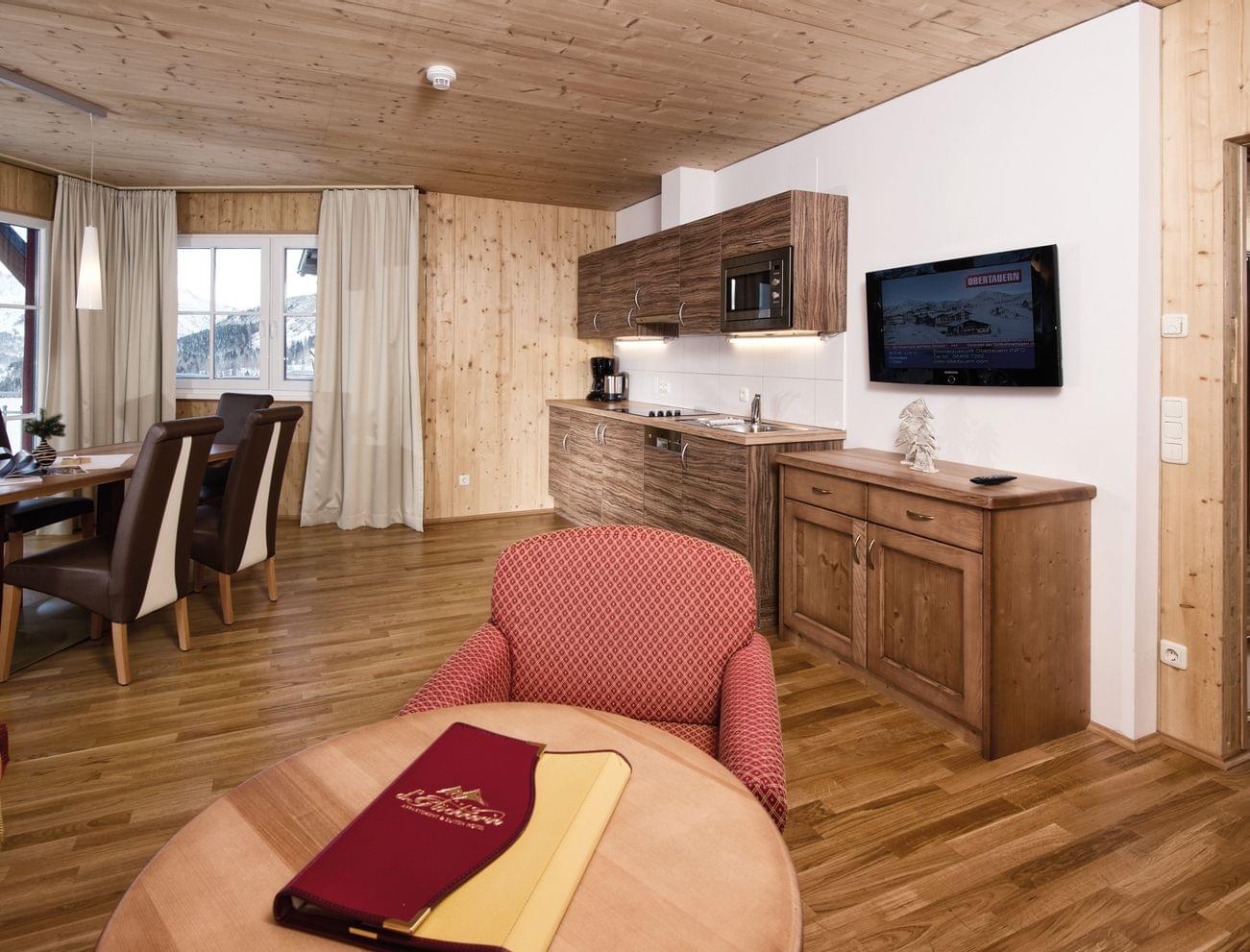 Modern alpine hotel suite with kitchenette, dining area and mountain view