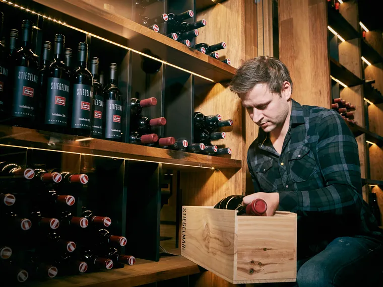 Man organizing red wine bottles in a modern wine cellar