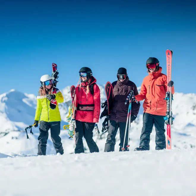 Gruppe von Skifahrern mit Ausrüstung auf verschneitem Berg unter blauem Himmel