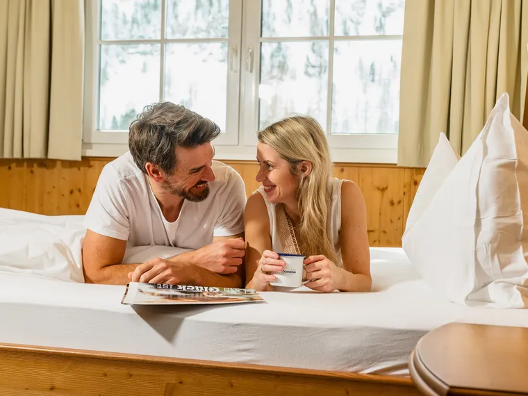 Couple relaxing in hotel room with coffee and magazine during winter vacation